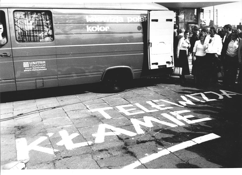 Obok ciężarówki promującej kolorową telewizję, na ziemi wymalowano hasło głoszące "Telewizja kłamie".